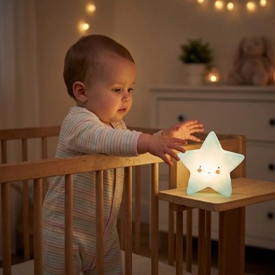 Veilleuse bébé  tendant la main vers une veilleuse étoile